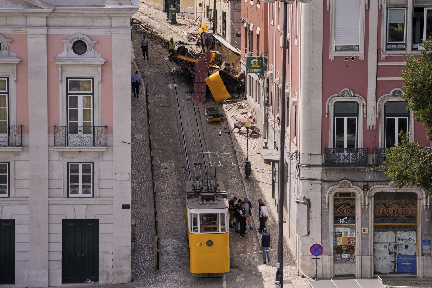 Etterforskere jobber på stedet etter trikkeulykken i Lisboa. En tysk mann som var antatt død i ulykken, er likevel i live og ligger hardt skadet på sykehus.